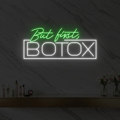 Photo of the 'But first, BOTOX' neon sign glowing in green against a styled interior wall.
