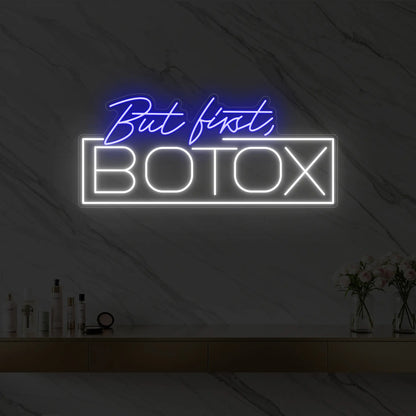 Photo of the 'But first, BOTOX' neon sign glowing in deep blue against a styled interior wall.
