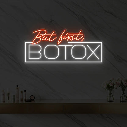 Photo of the 'But first, BOTOX' neon sign glowing in golden yellow against a styled interior wall.