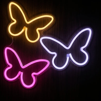 Butterfly trio LED neon sign with yellow, pink and lavender-white illumination on clear acrylic backing.