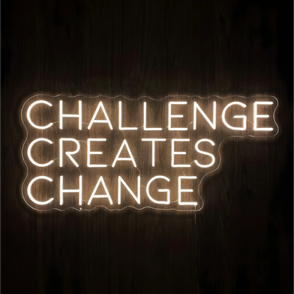 “CHALLENGE CREATES CHANGE” LED Neon Sign glowing in warm white uppercase letters across three lines on clear acrylic against a dark wood background, suited to home offices and fitness spaces.
