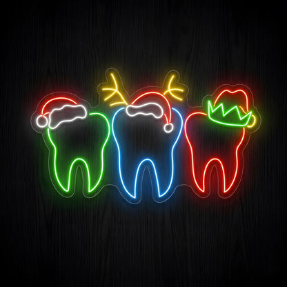 Colorful Christmas Teeth LED neon sign featuring green, blue, and red tooth outlines wearing Santa hats, reindeer antlers, and an elf hat on clear acrylic backing for dental clinic Christmas decor.