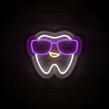 Cool Tooth Sunglasses LED neon sign featuring a smiling white tooth wearing glowing purple sunglasses on clear acrylic backing for pediatric dental clinic and dentist office wall decor.