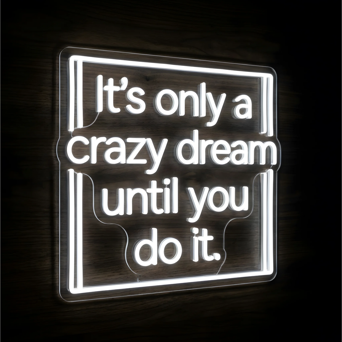 It's Only a Crazy Dream LED Neon Sign displaying “It’s only a crazy dream until you do it” in white lettering inside a rectangular neon frame on clear acrylic backing against a dark wood background, suited to home offices and creative studios.