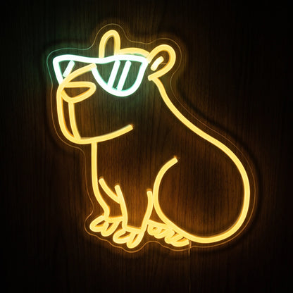 Cute capybara LED neon sign with warm yellow animal outline, cool white sunglasses, and clear acrylic backing.