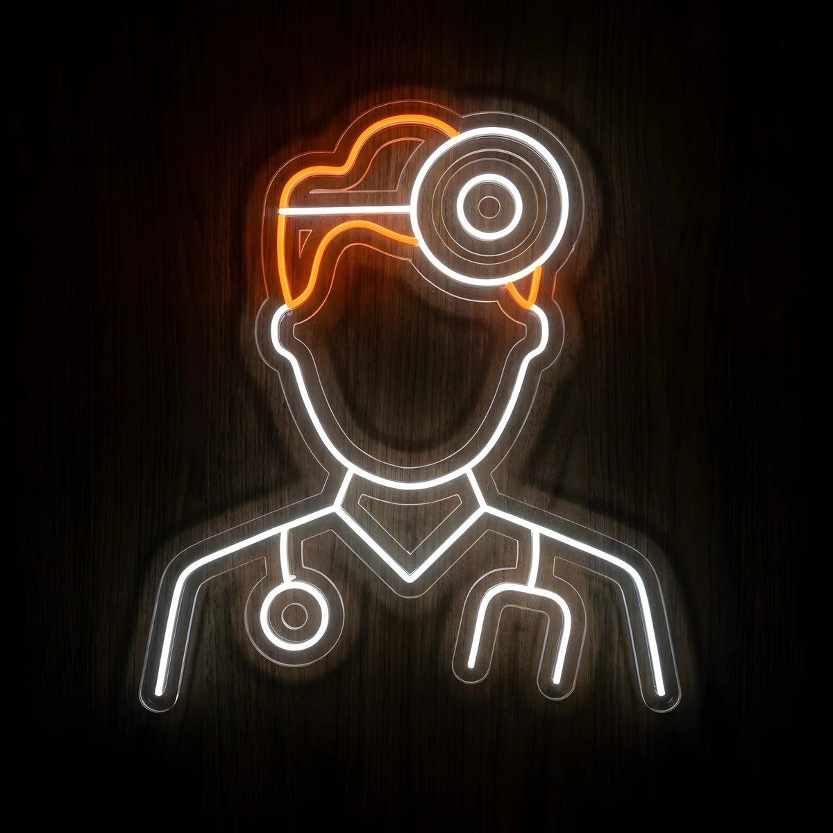 Doctor Head Mirror LED Neon Sign featuring a white neon physician outline with orange hair, a circular head mirror, and a stethoscope on clear acrylic backing against a dark wooden wall.