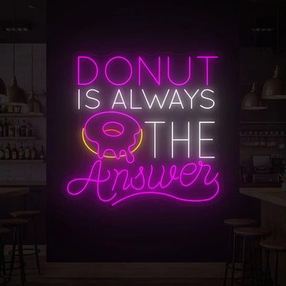 Photo of the 'DONUT IS ALWAYS THE ANSWER' neon sign glowing in multi-color against a styled interior wall.