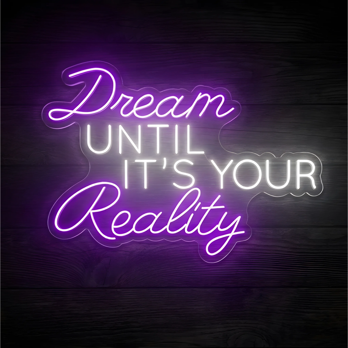 Dream Until It’s Your Reality LED Neon Sign with purple script for “Dream” and “Reality” and white uppercase “UNTIL IT’S YOUR,” on clear acrylic against a dark wood background, suited to bedrooms and creative studios.