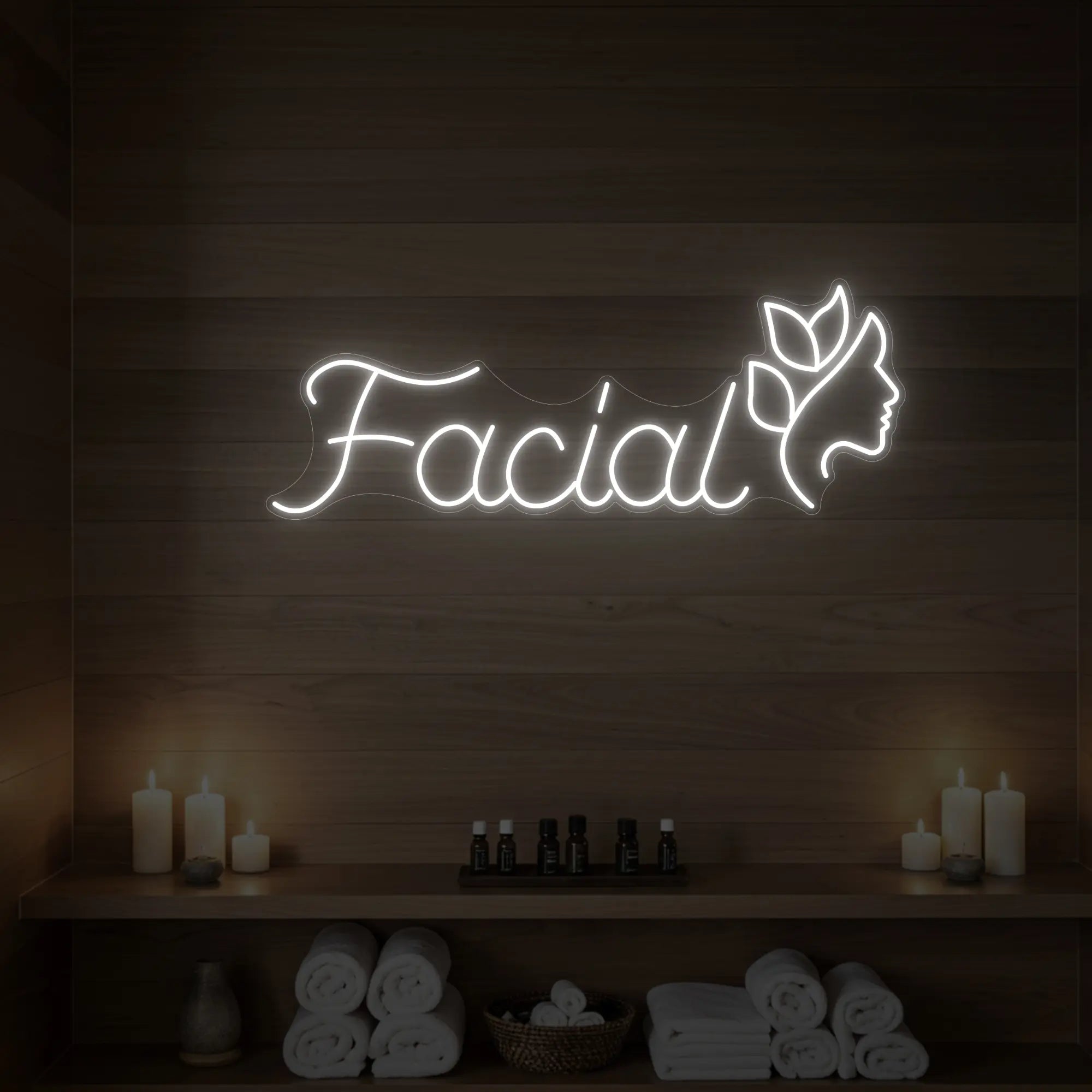 Photo of the 'Facial' neon sign with a botanical face silhouette glowing in cool white against a styled interior wall.