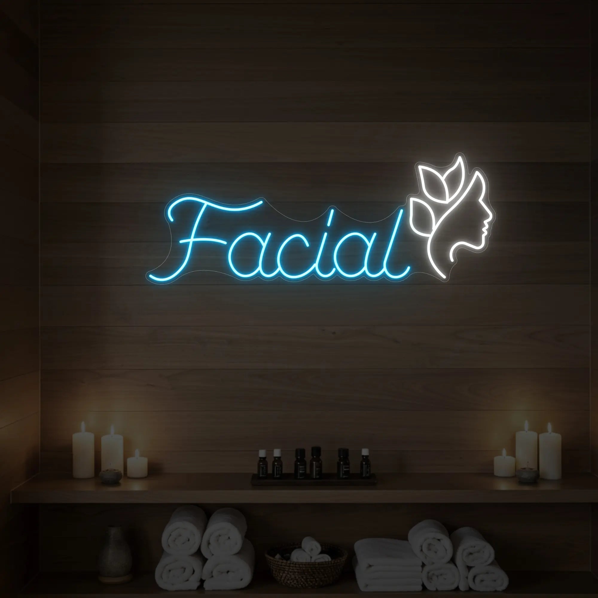 Photo of the 'Facial' neon sign with a botanical face silhouette glowing in ice blue against a styled interior wall.