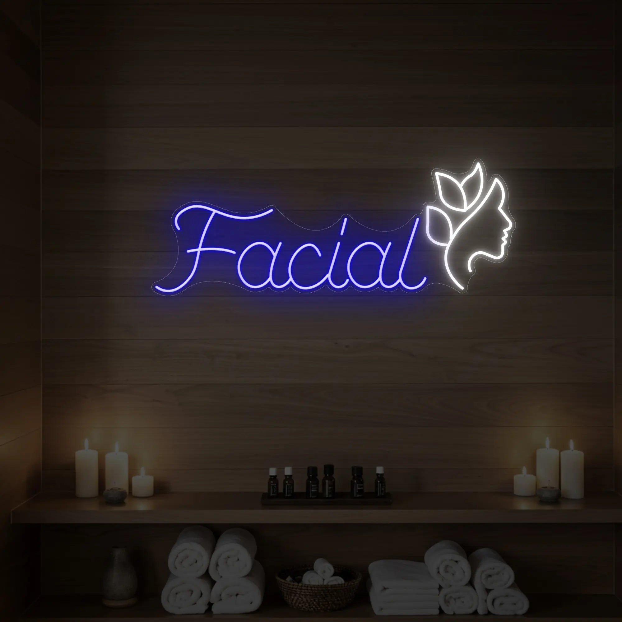 Photo of the 'Facial' neon sign with a botanical face silhouette glowing in deep blue against a styled interior wall.