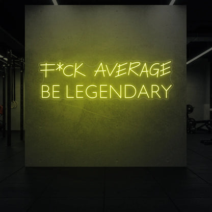 'F*ck Average Be Legendary' neon sign glowing in lemon yellow against a styled interior wall.