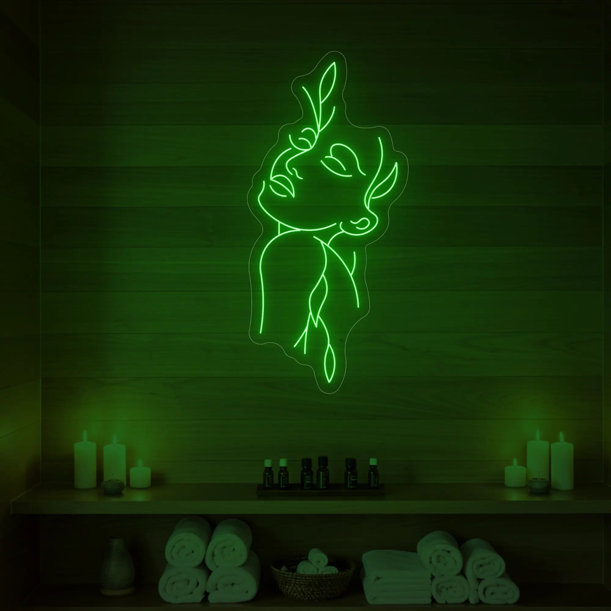Photo of the 'Flower Girl' neon sign featuring a minimalist face and leaf line art glowing in green against a styled interior wall.