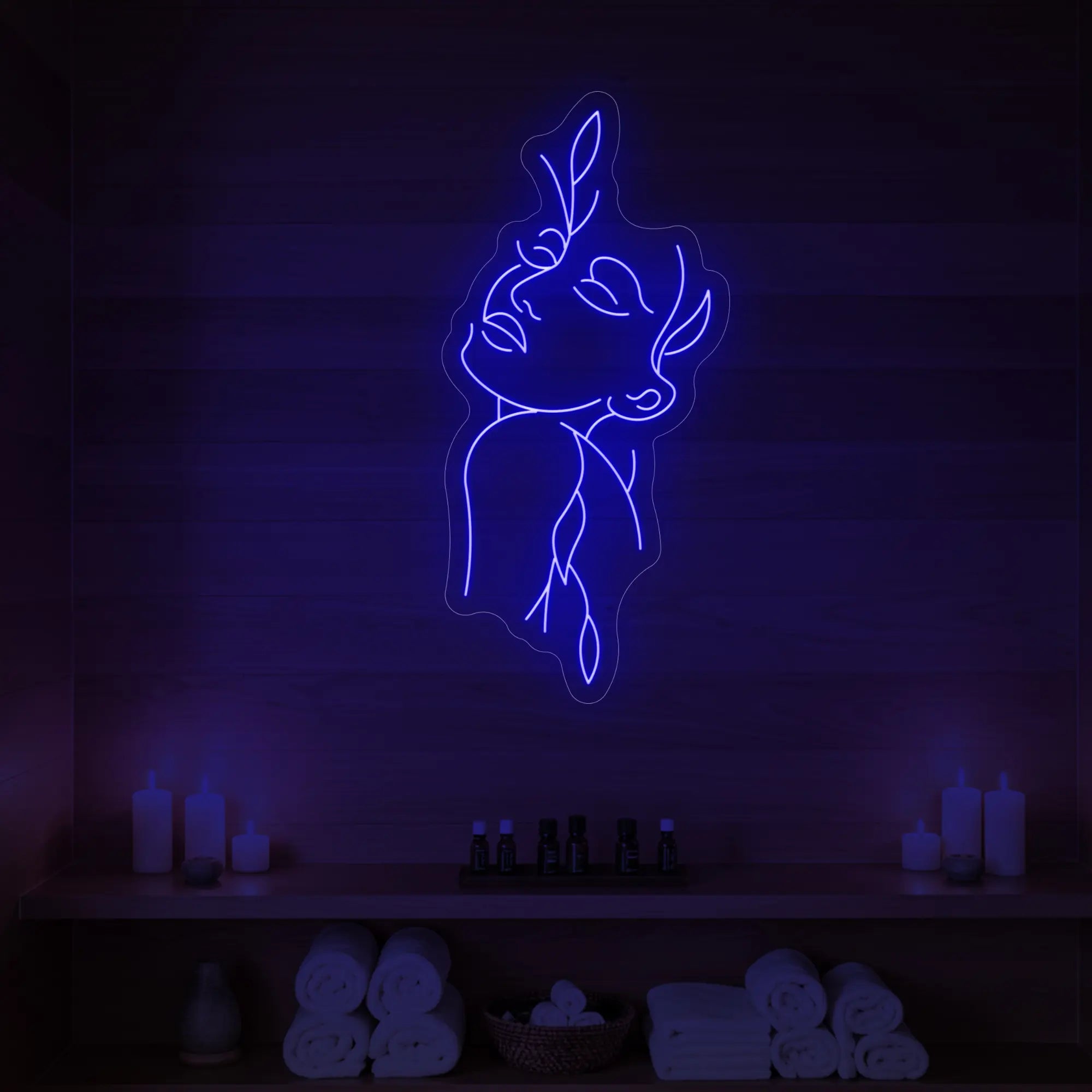 Photo of the 'Flower Girl' neon sign featuring a minimalist face and leaf line art glowing in deep blue against a styled interior wall.