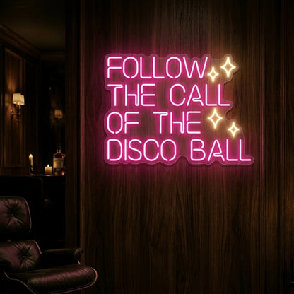 Photo of the 'Follow the Call of the Disco Ball' neon sign glowing in light pink and warm white against a styled interior wall.
