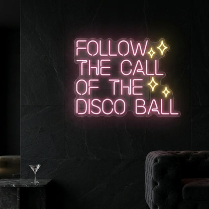Photo of the 'Follow the Call of the Disco Ball' neon sign glowing in light pink and warm white against a styled interior wall.