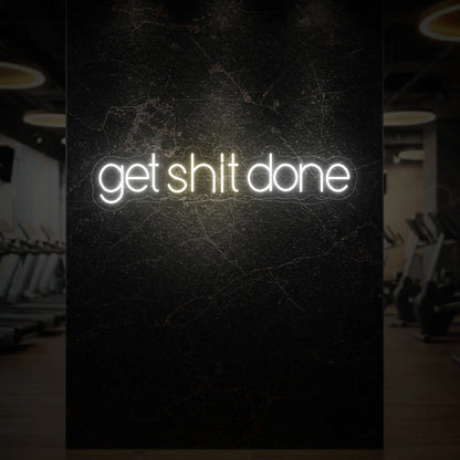  'Get Shit Done' neon sign glowing in warm white against a styled interior wall.
