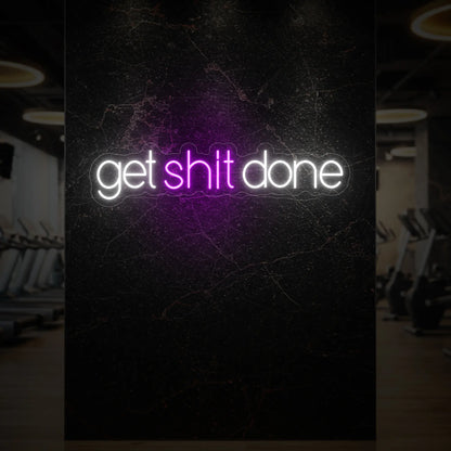  'Get Shit Done' neon sign glowing in deep pink against a styled interior wall.
