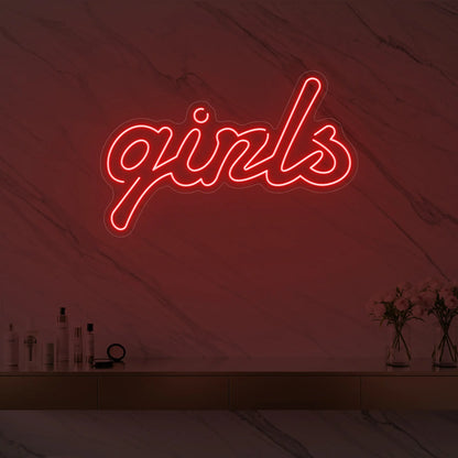 Photo of the 'girls' neon sign in playful script glowing in red against a styled interior wall.