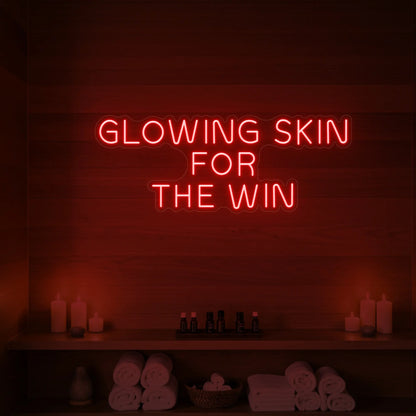 Photo of the 'GLOWING SKIN FOR THE WIN' neon sign glowing in red against a styled interior wall.