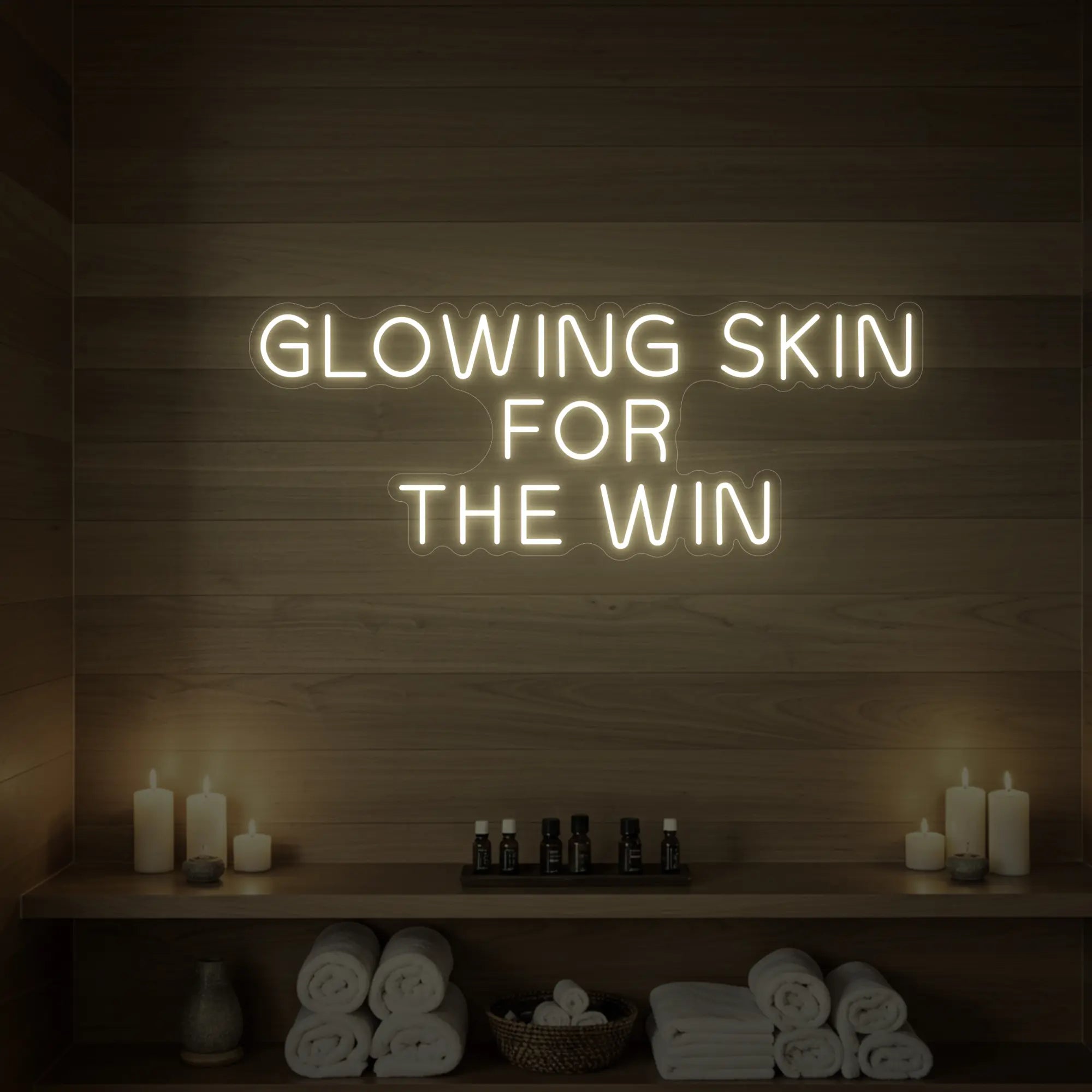 Photo of the 'GLOWING SKIN FOR THE WIN' neon sign glowing in warm white against a styled interior wall.