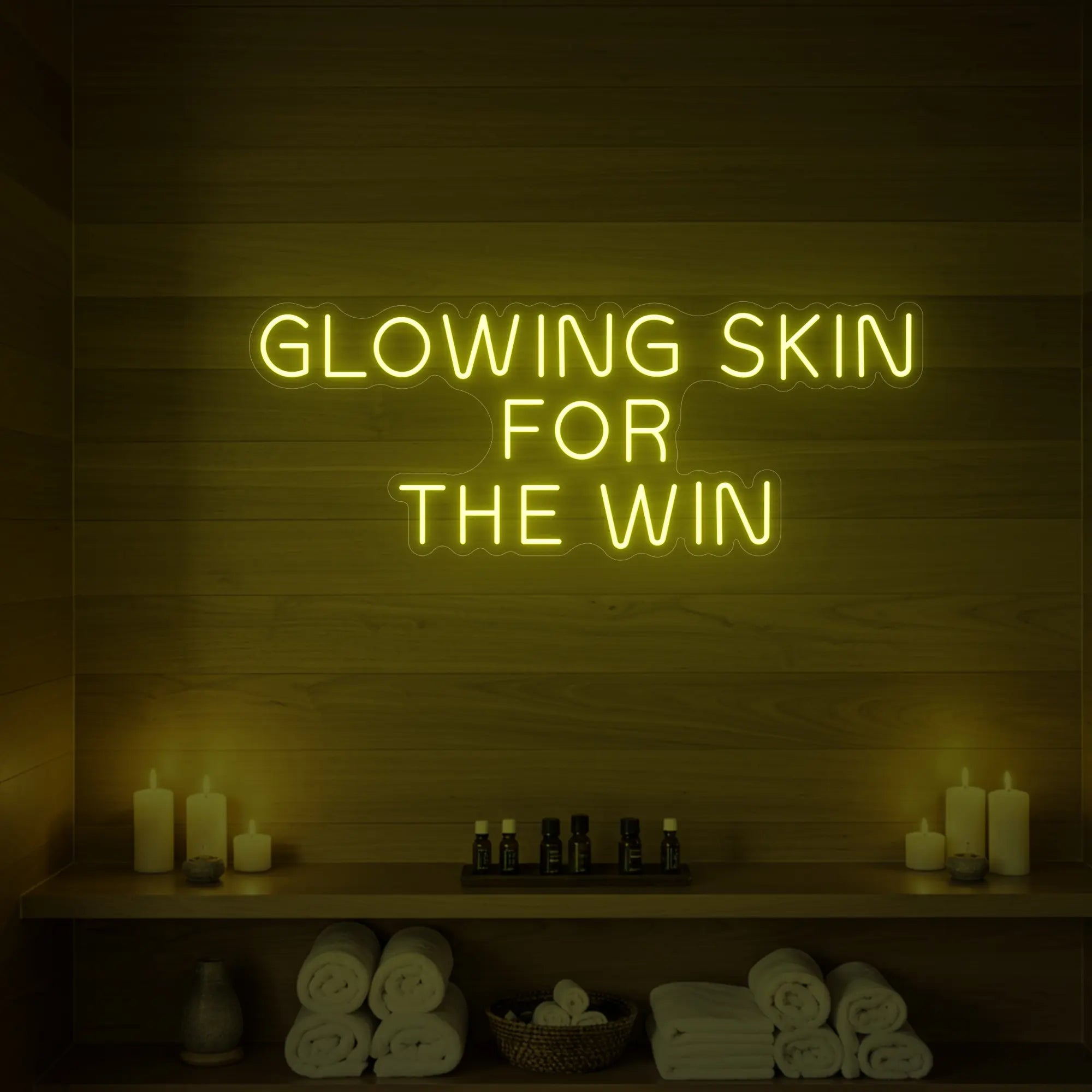 Photo of the 'GLOWING SKIN FOR THE WIN' neon sign glowing in lemon yellow against a styled interior wall.