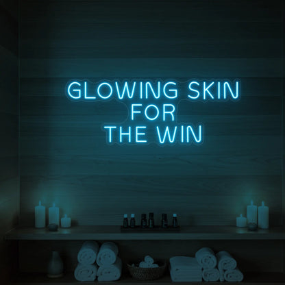 Photo of the 'GLOWING SKIN FOR THE WIN' neon sign glowing in ice blue against a styled interior wall.