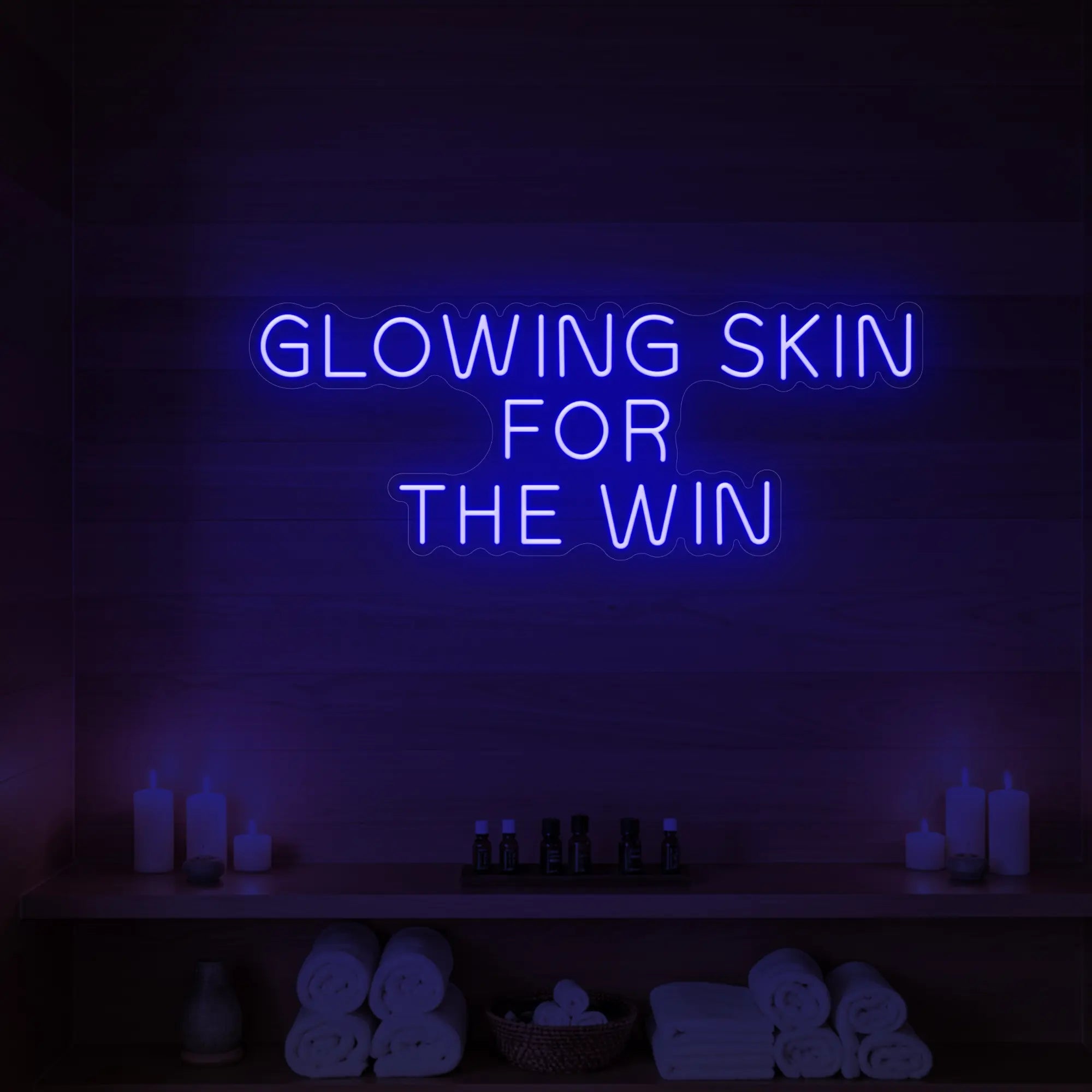 Photo of the 'GLOWING SKIN FOR THE WIN' neon sign glowing in deep blue against a styled interior wall.