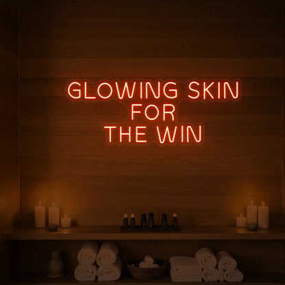 Photo of the 'GLOWING SKIN FOR THE WIN' neon sign glowing in golden yellow against a styled interior wall.