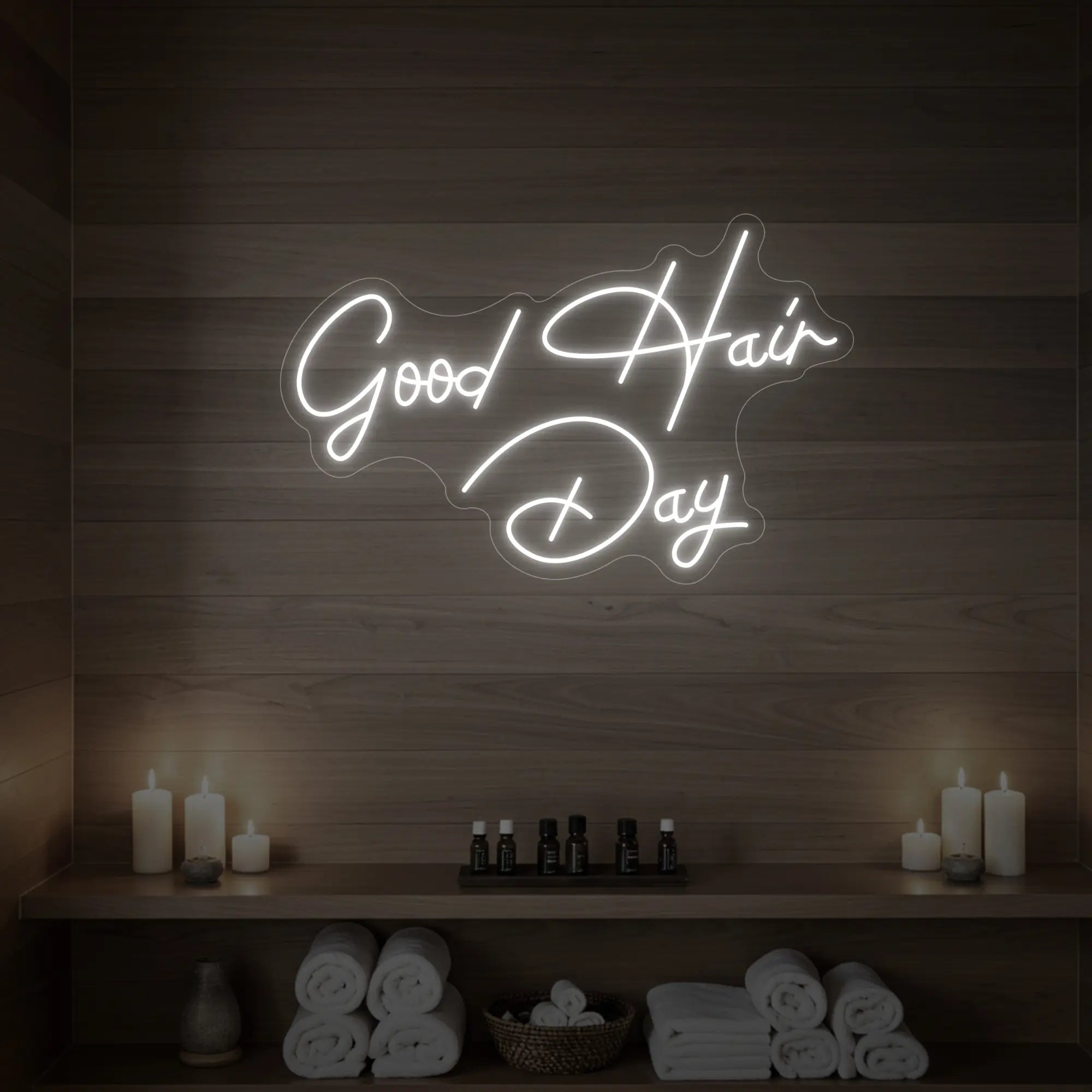 Photo of the 'Good Hair Day' neon sign in cursive glowing in cool white against a styled interior wall.