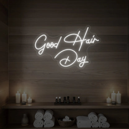 Photo of the 'Good Hair Day' neon sign in cursive glowing in cool white against a styled interior wall.