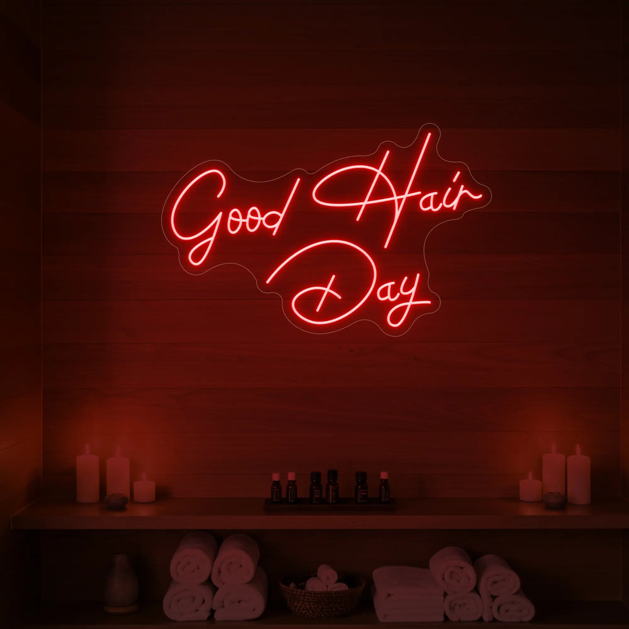 Photo of the 'Good Hair Day' neon sign in cursive glowing in red against a styled interior wall.