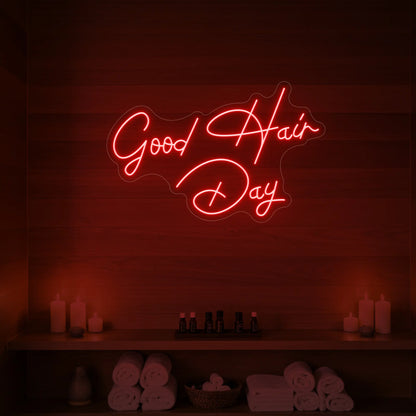 Photo of the 'Good Hair Day' neon sign in cursive glowing in red against a styled interior wall.