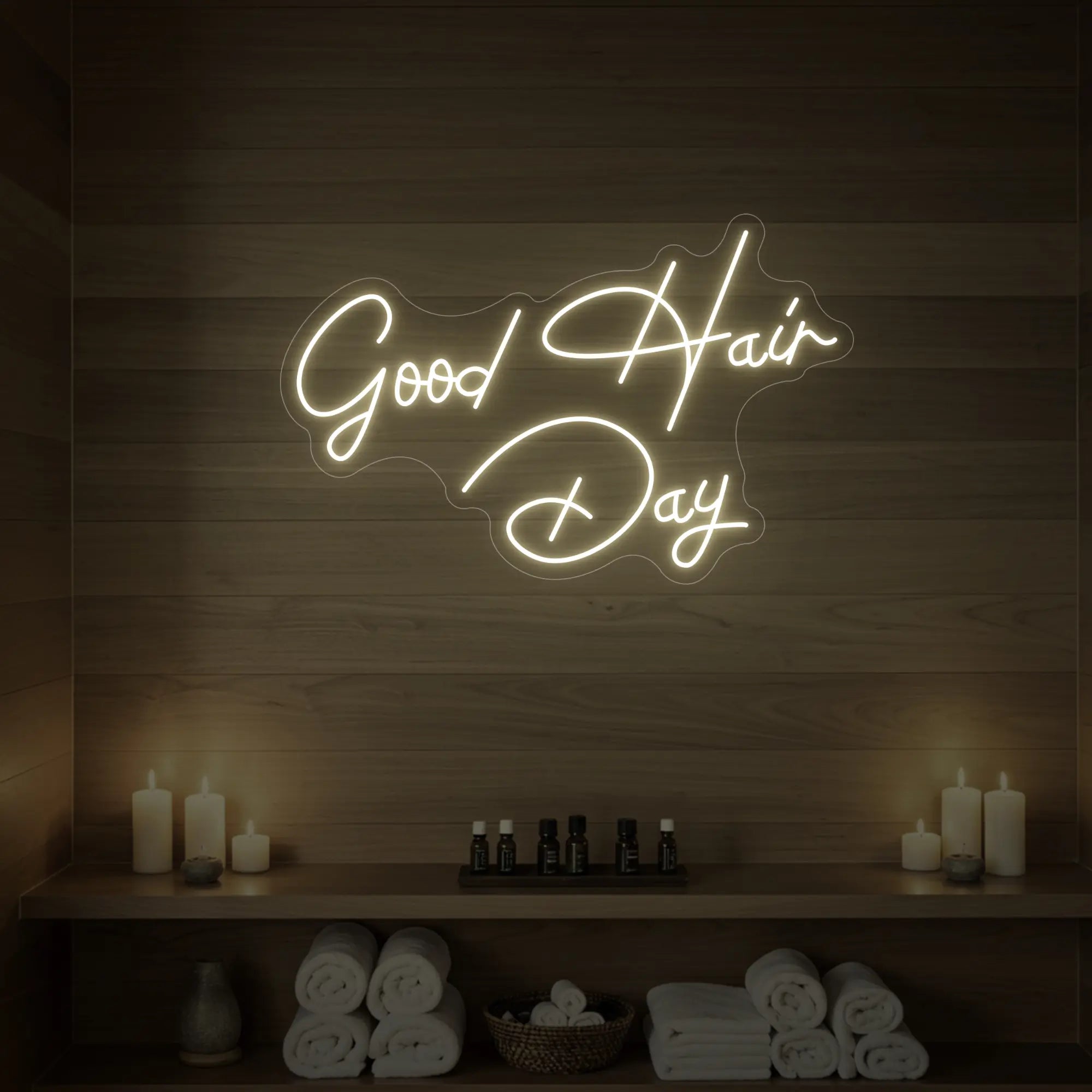 Photo of the 'Good Hair Day' neon sign in cursive glowing in warm white against a styled interior wall.