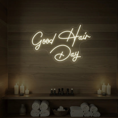 Photo of the 'Good Hair Day' neon sign in cursive glowing in warm white against a styled interior wall.