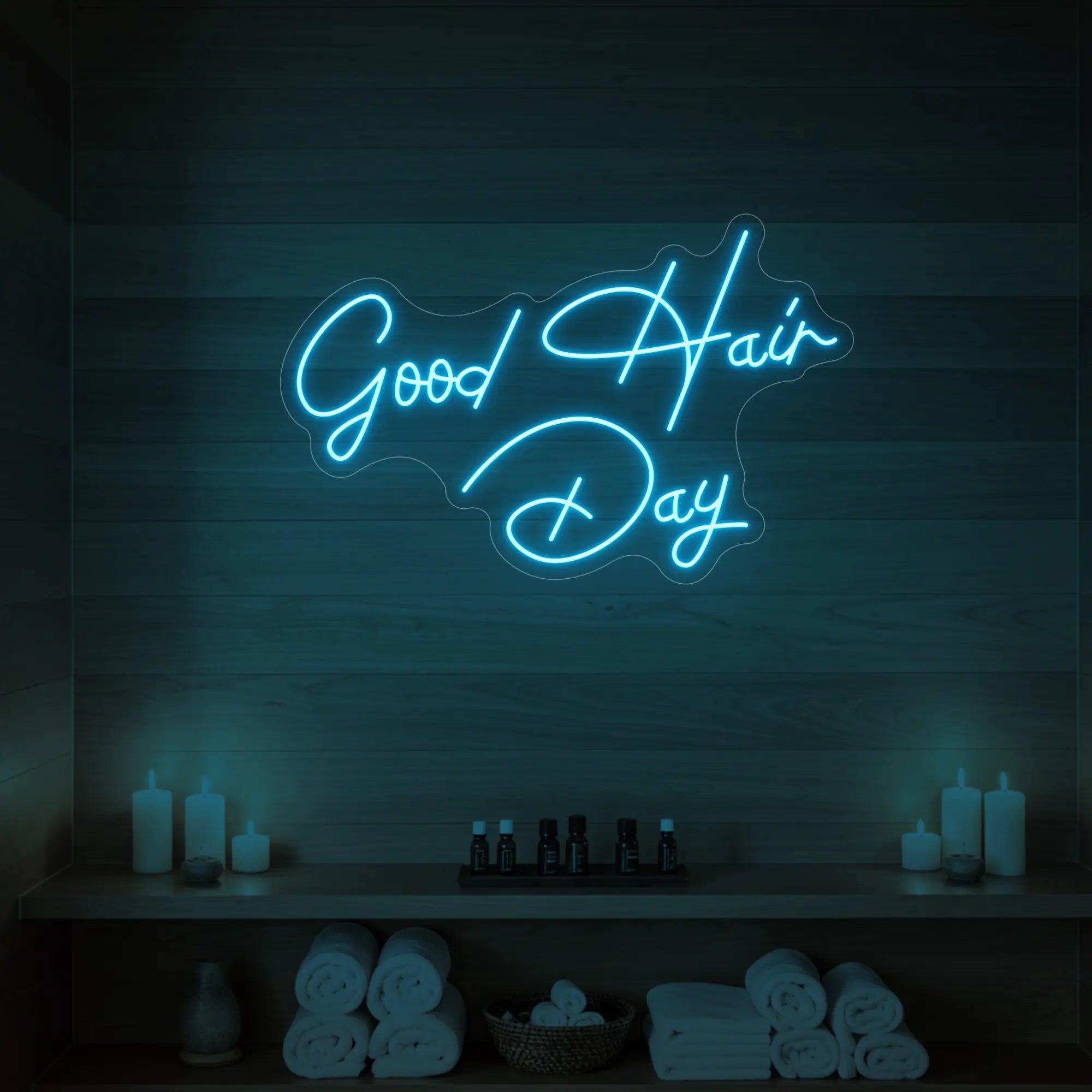 Photo of the 'Good Hair Day' neon sign in cursive glowing in ice blue against a styled interior wall.