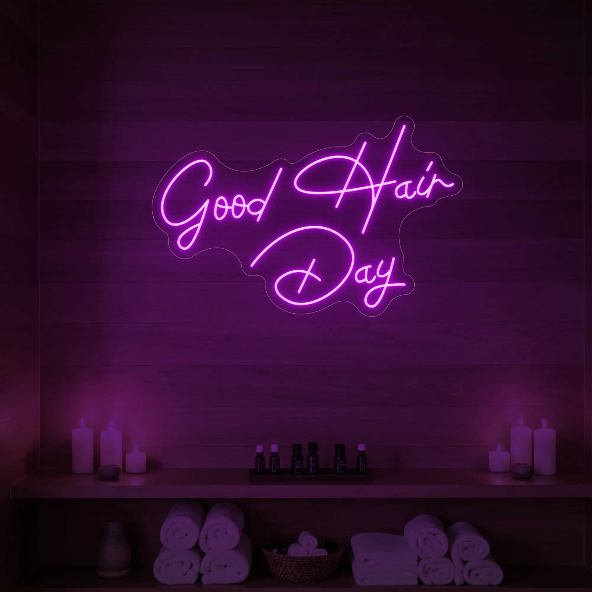 Photo of the 'Good Hair Day' neon sign in cursive glowing in deep pink against a styled interior wall.