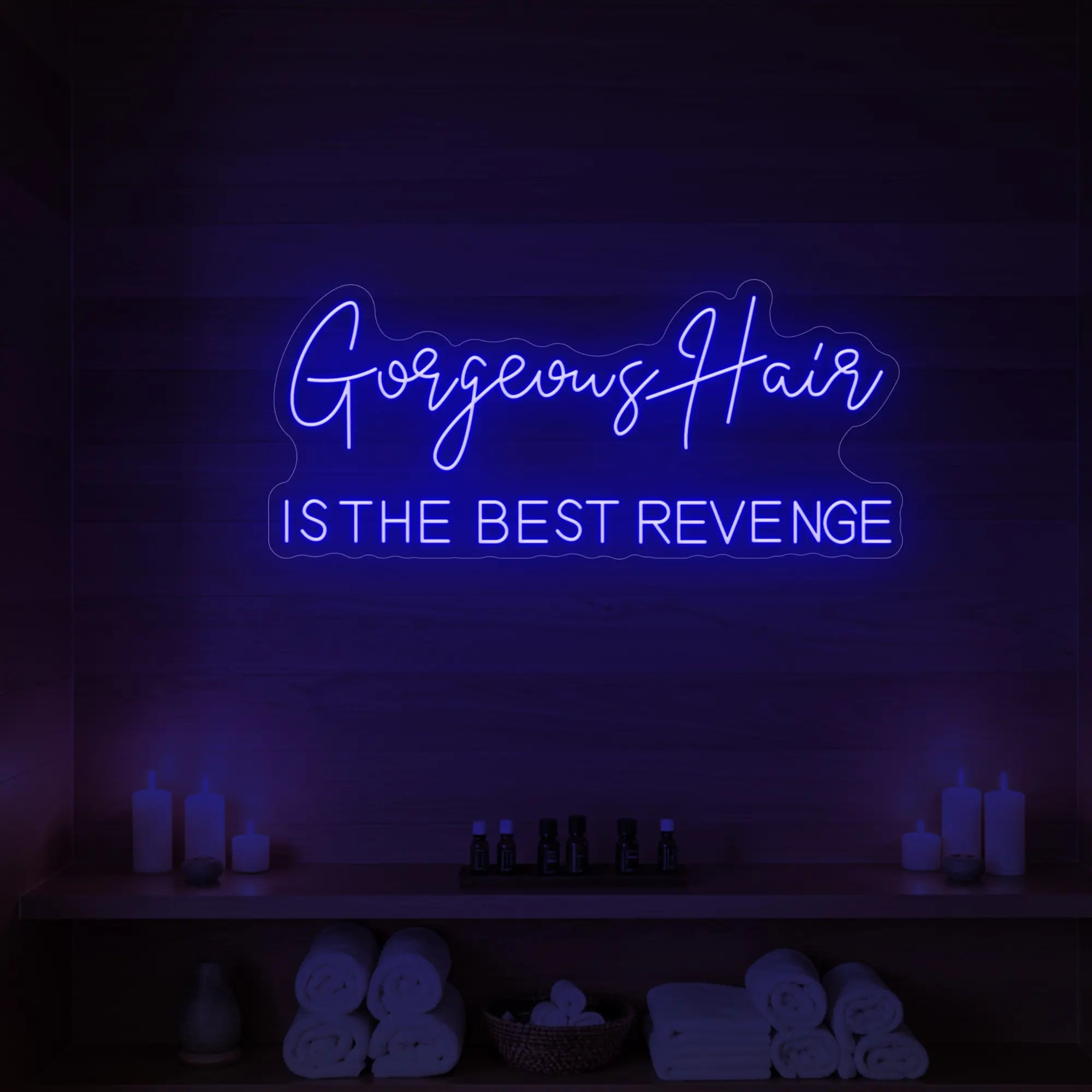 Photo of the 'Gorgeous Hair is the Best Revenge' neon sign glowing in deep blue against a styled interior wall.