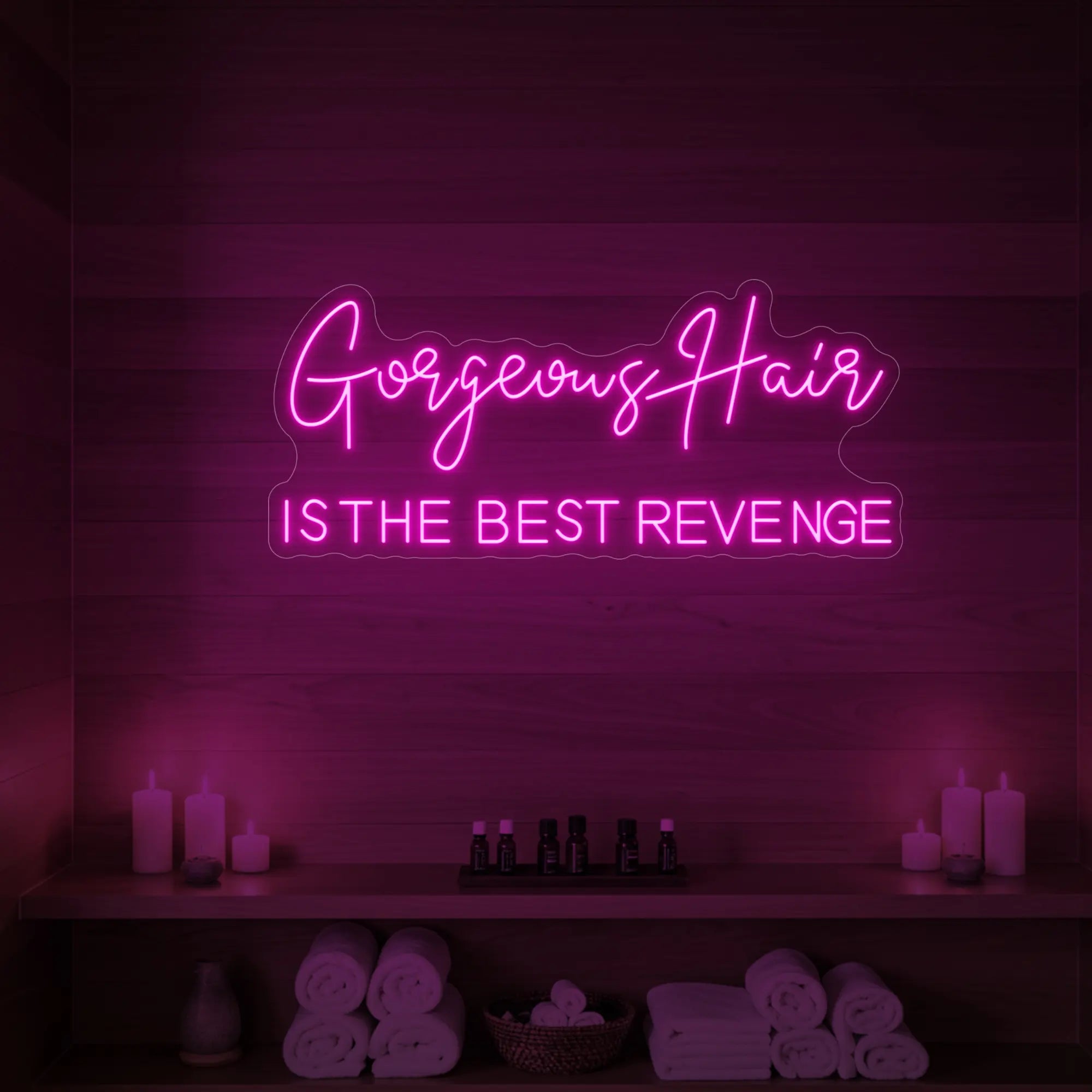 Photo of the 'Gorgeous Hair is the Best Revenge' neon sign glowing in light pink against a styled interior wall.