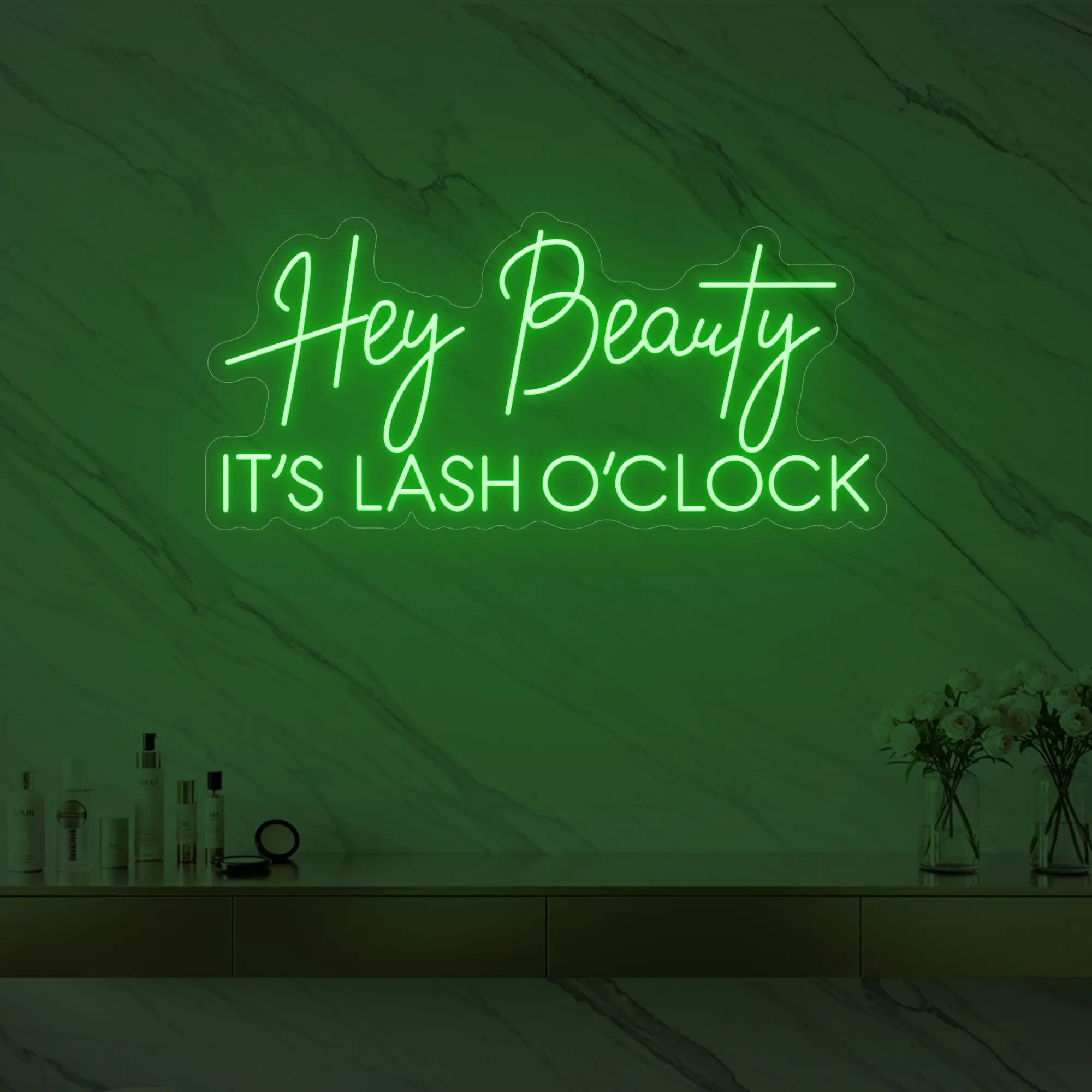 Photo of the 'Hey Beauty IT’S LASH O’CLOCK' neon sign glowing in green against a styled interior wall.