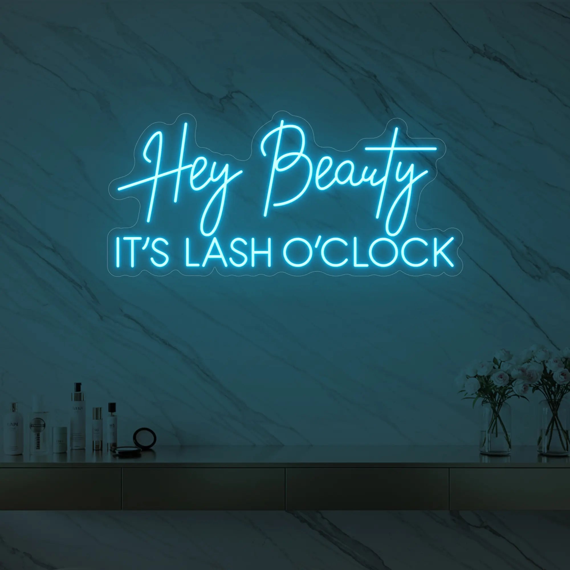 Photo of the 'Hey Beauty IT’S LASH O’CLOCK' neon sign glowing in ice blue against a styled interior wall.