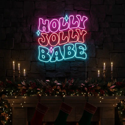 Photo of the 'Holly Jolly Babe' neon sign glowing in multicolor against a styled interior wall.