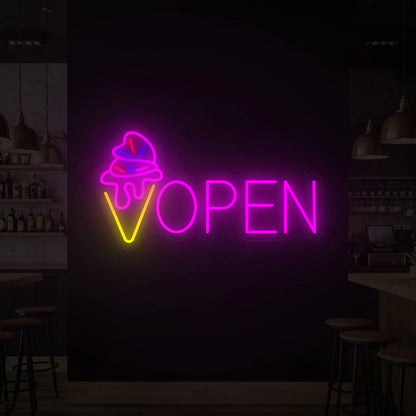 Photo of the 'ICE CREAM OPEN' neon sign glowing in multi-color against a styled interior wall.