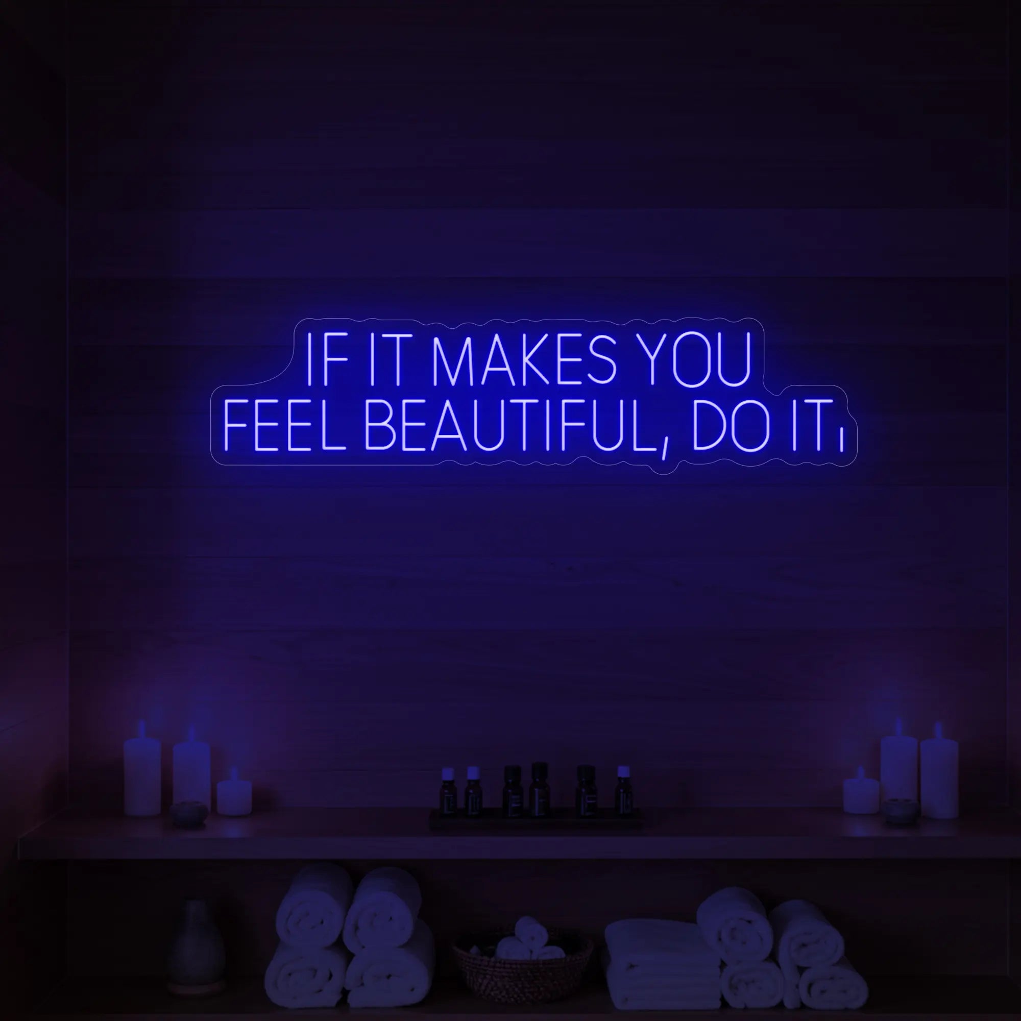 Photo of the 'IF IT MAKES YOU FEEL BEAUTIFUL, DO IT.' neon sign glowing in deep blue against a styled interior wall.