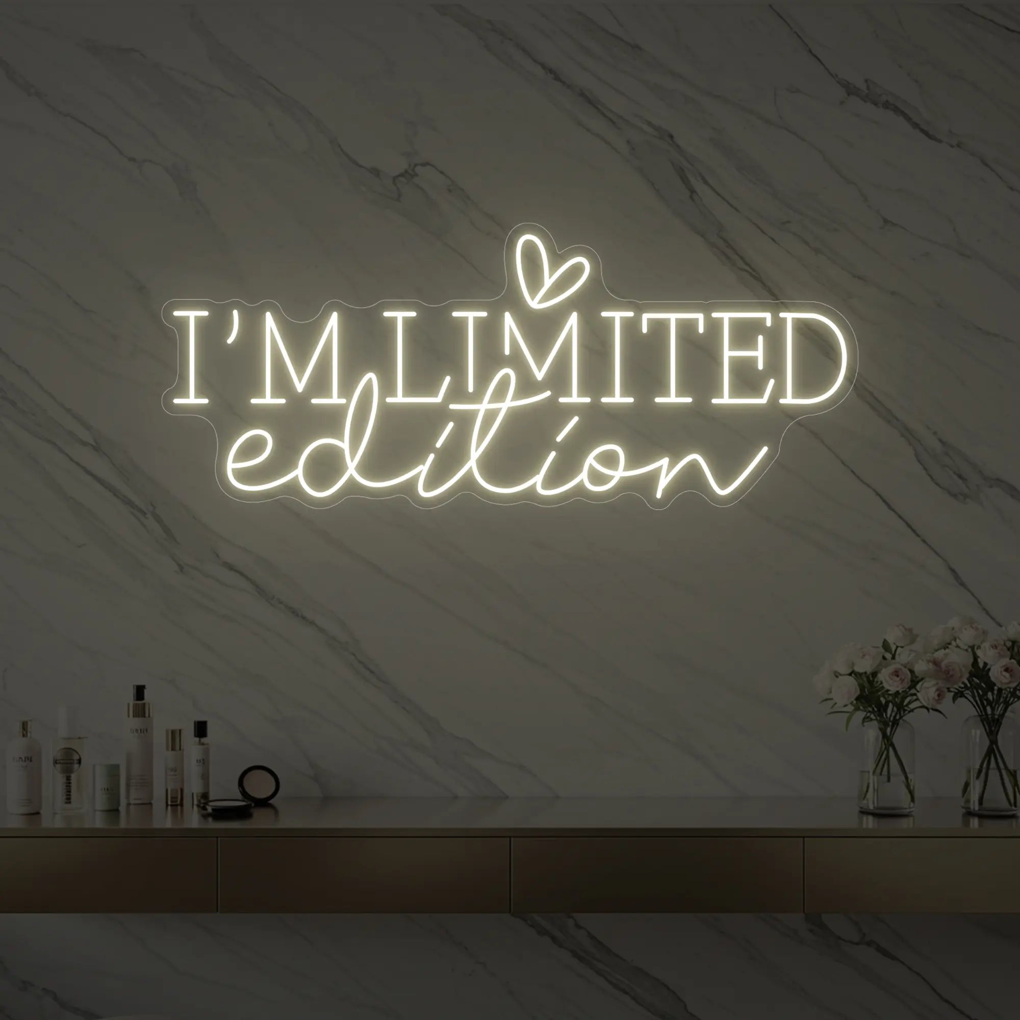 Photo of the 'I’M LIMITED edition' neon sign with a heart icon glowing in warm white against a styled interior wall.