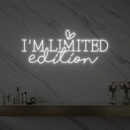 Photo of the 'I’M LIMITED edition' neon sign with a heart icon glowing in cool white against a styled interior wall.