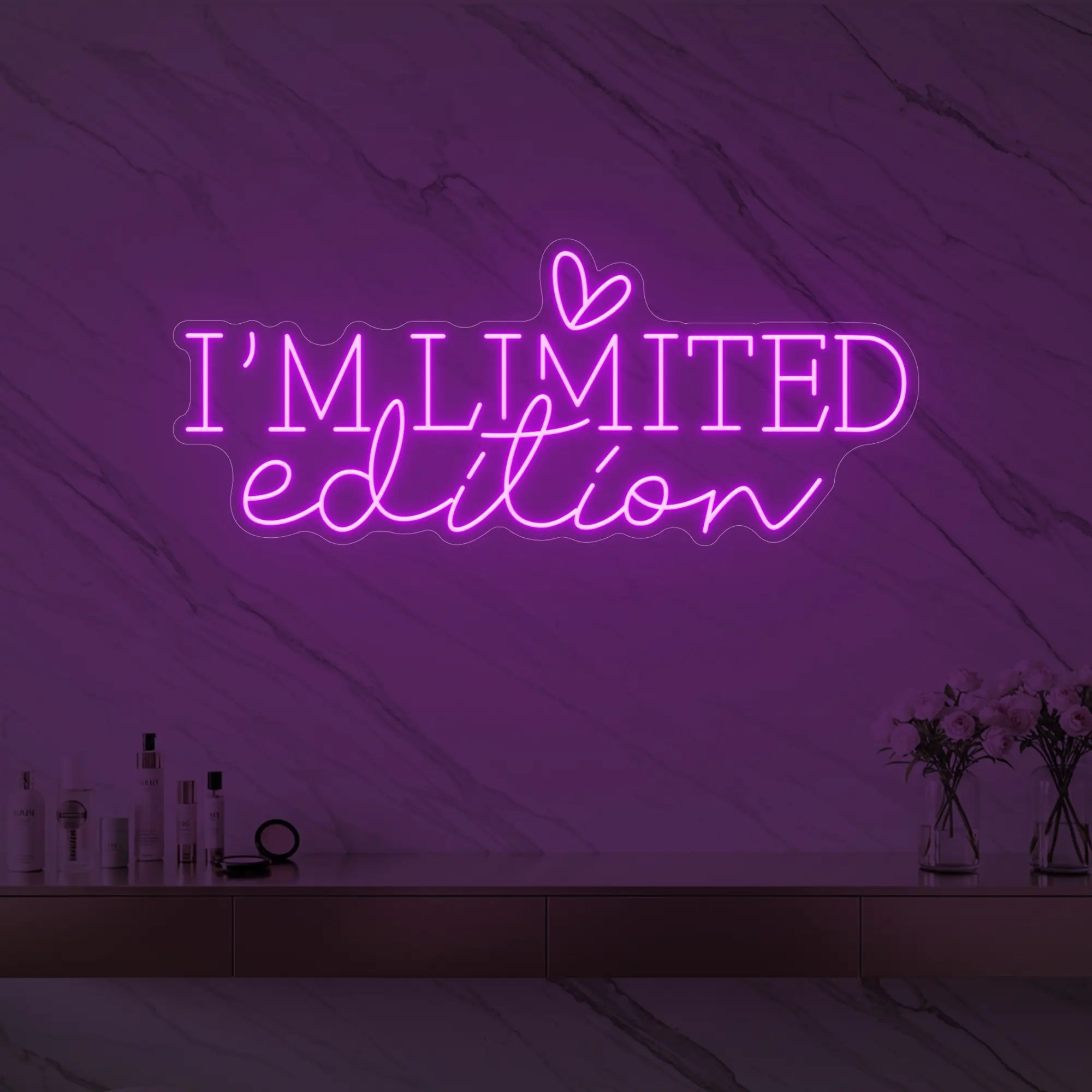 Photo of the 'I’M LIMITED edition' neon sign with a heart icon glowing in deep pink against a styled interior wall.