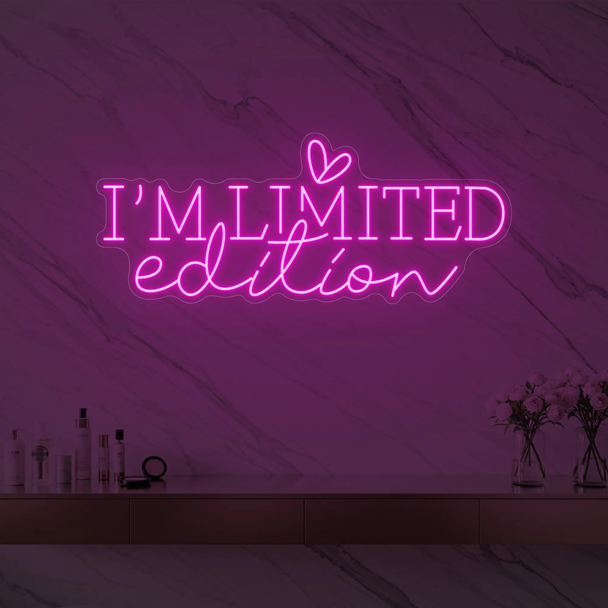 Photo of the 'I’M LIMITED edition' neon sign with a heart icon glowing in light pink against a styled interior wall.
