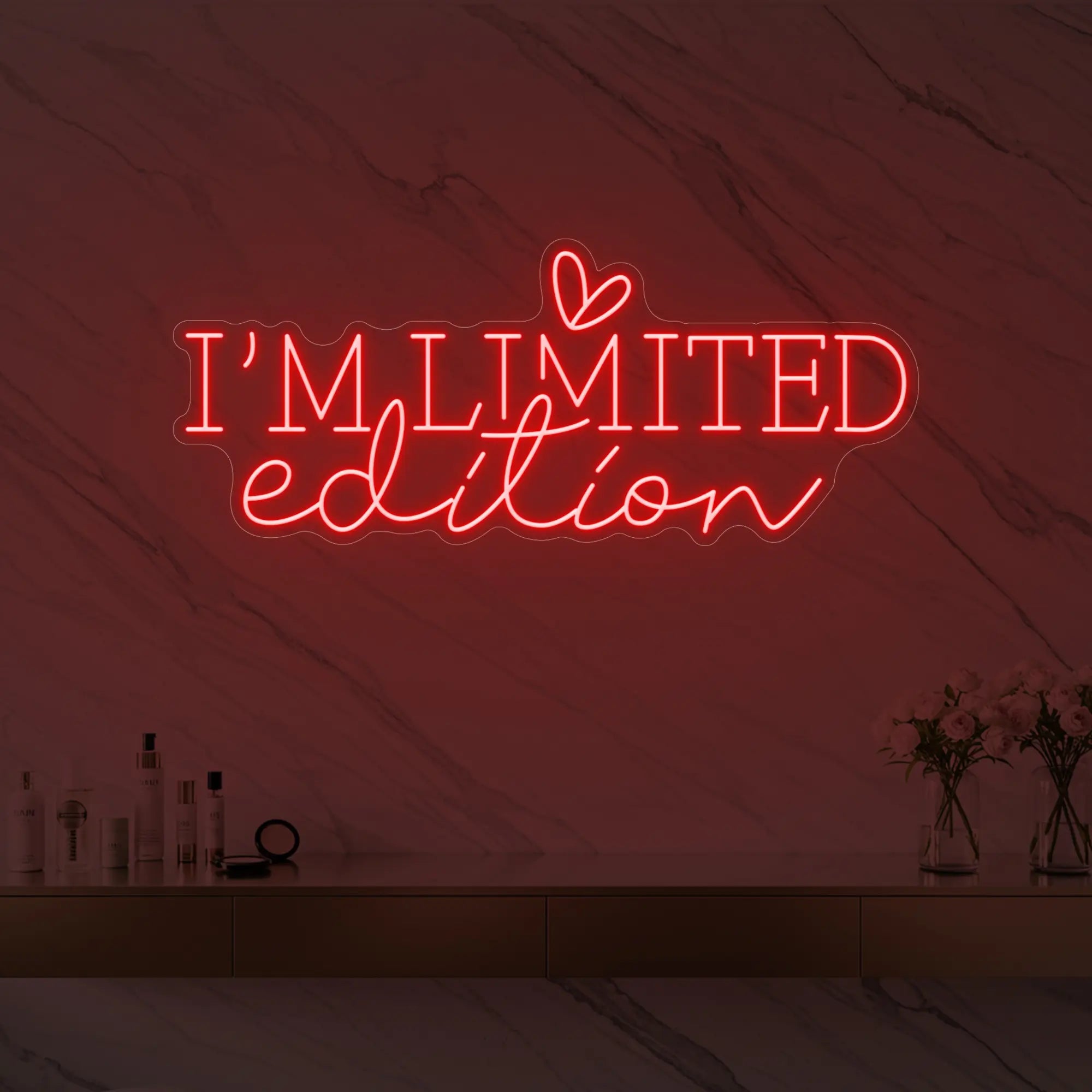 Photo of the 'I’M LIMITED edition' neon sign with a heart icon glowing in red against a styled interior wall.