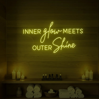 Photo of the 'INNER glow MEETS OUTER Shine' neon sign glowing in lemon yellow against a styled interior wall.